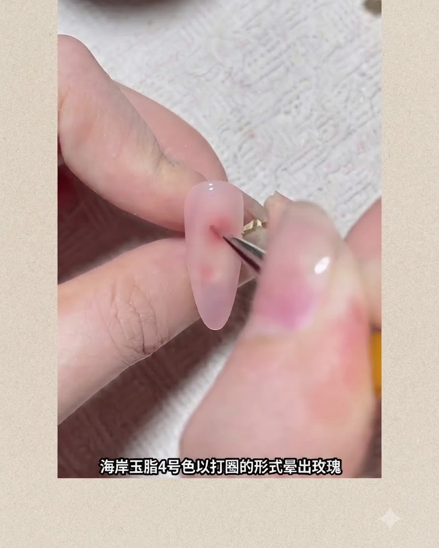 A fine nail art brush drawing a reddish circular pigment dot onto a pink gel-coated nail to form a blooming flower.