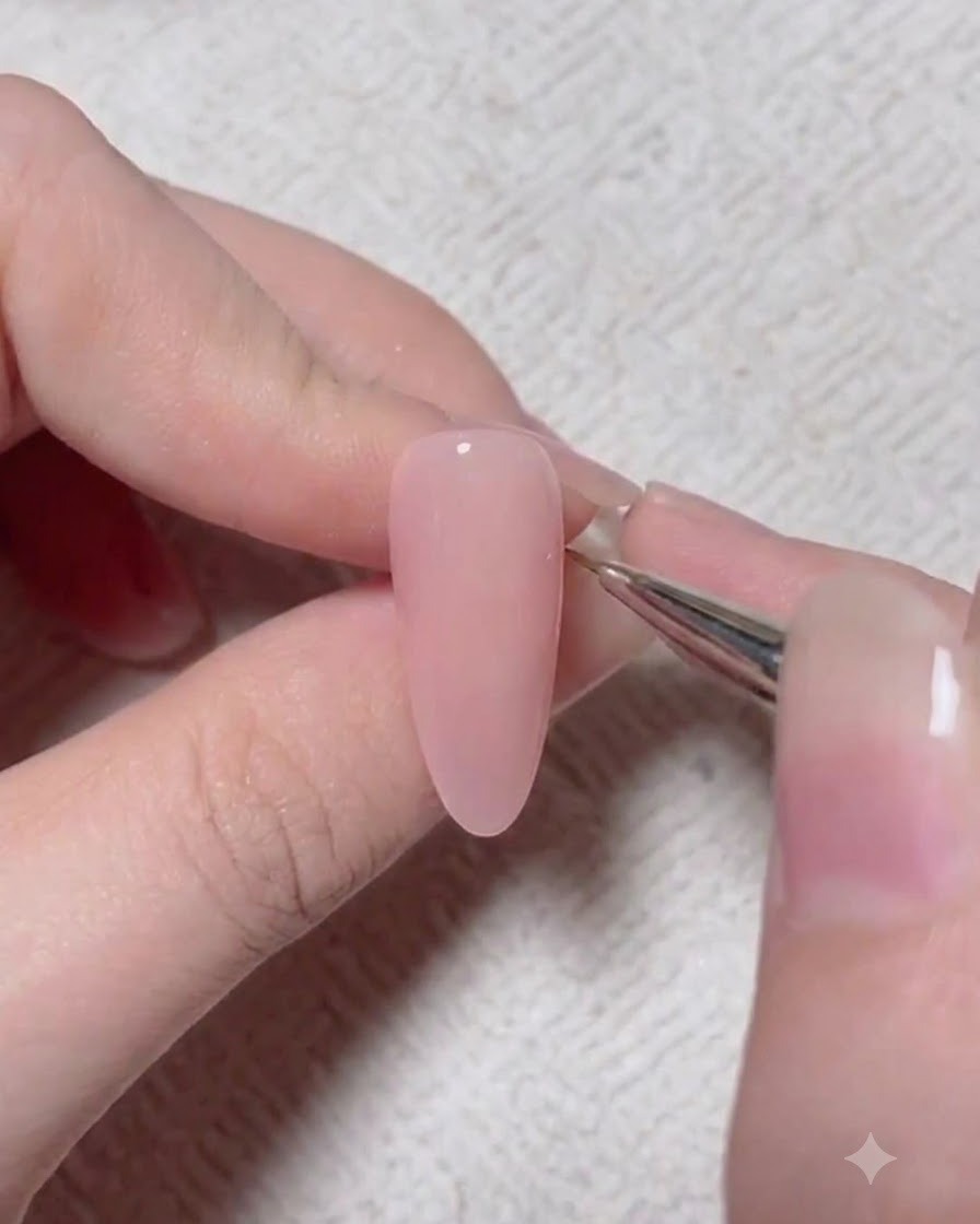 A detail brush applying a darker accent pigment onto a pink gel nail surface.