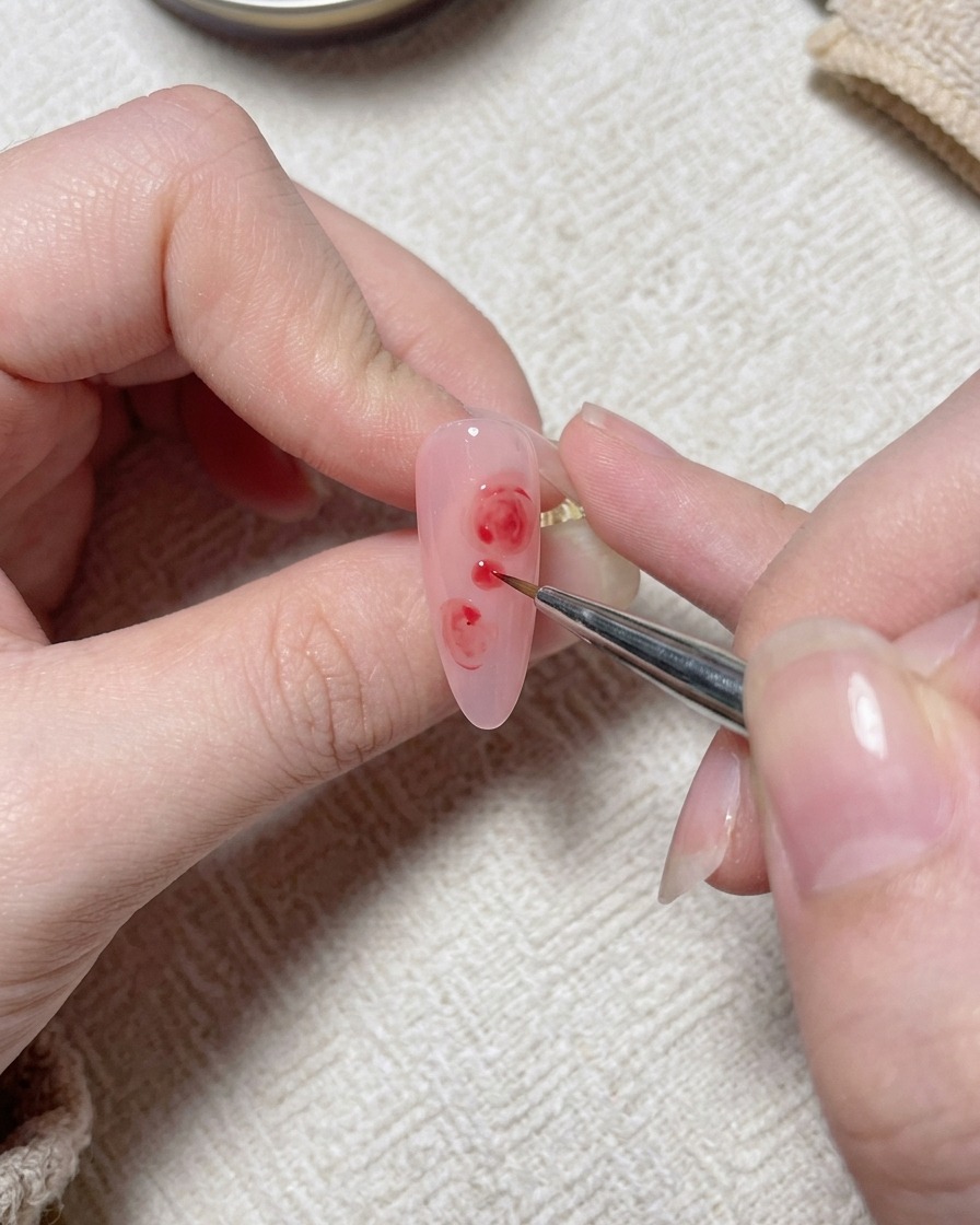 A fine brush applying small white dabbing details onto the pink rose design.