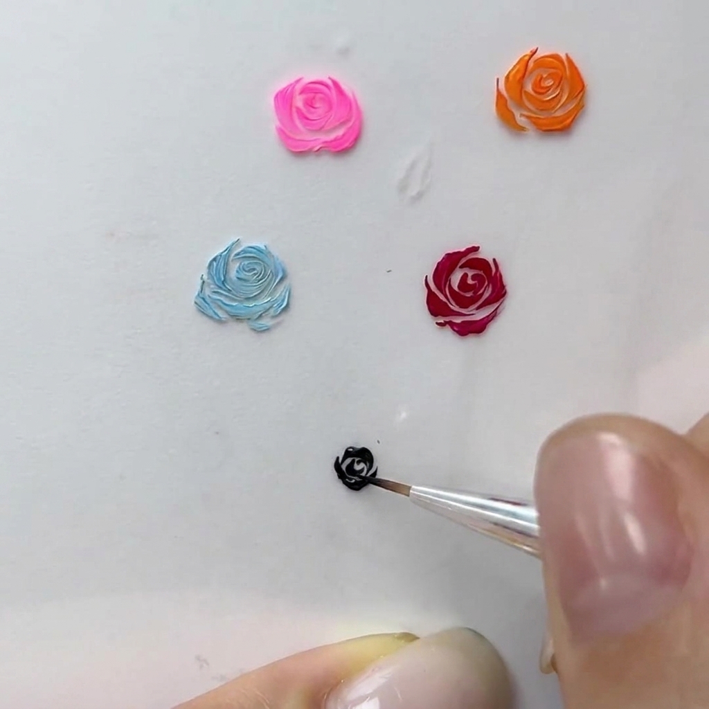 A macro view of a nail artist adding fine curved strokes to the border of a black gel rose.