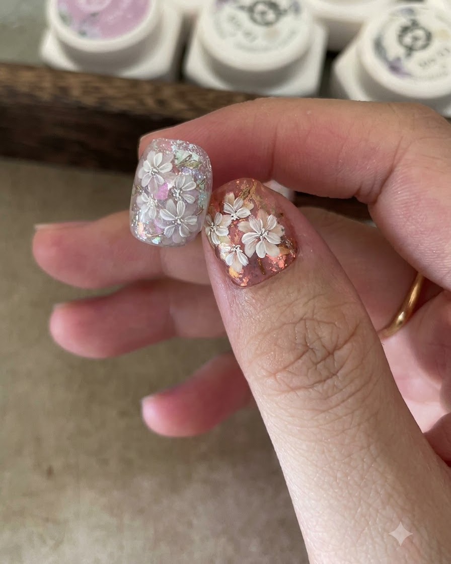 A brush applying a clear base coat onto a nail tip.