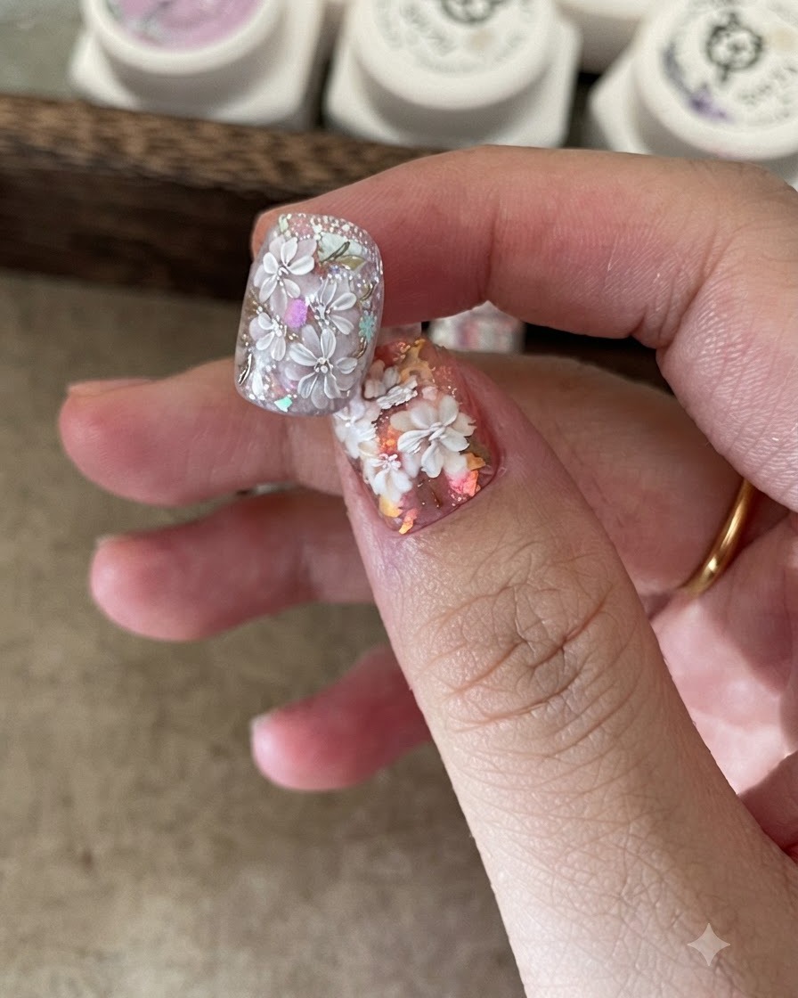 A small brush placing iridescent foil flakes onto a tacky nail base.