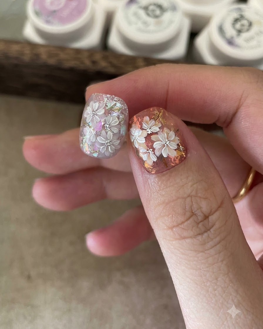 An applicator sponge rubbing gold mirror powder onto the painted leaf details of a nail.