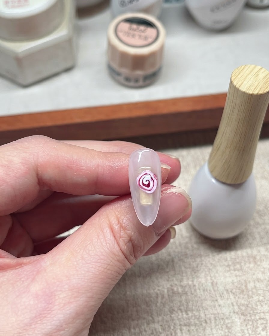 A completed red and white blooming gel rose design on a nail.