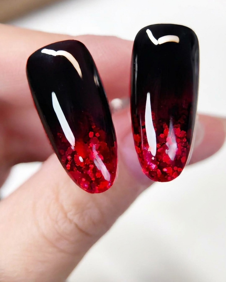 A close-up of a brush spreading sparkling red glitter flakes across the lower section of a dark-painted nail extension.