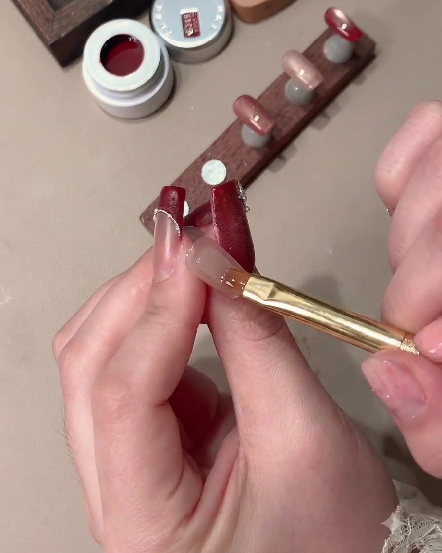 A magnet shaping cat-eye gel on a nail to create a wide-light effect with a clear French tip space.