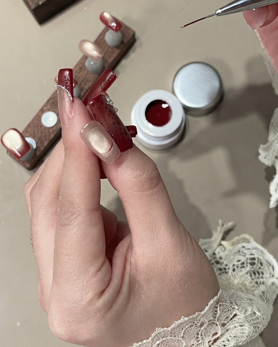 A liner brush filling in the French tip area with opaque red velvet gel.