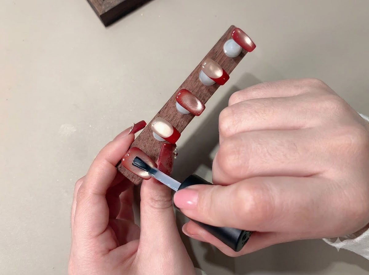 A brush applying a clear top coat to seal the finished nail art.