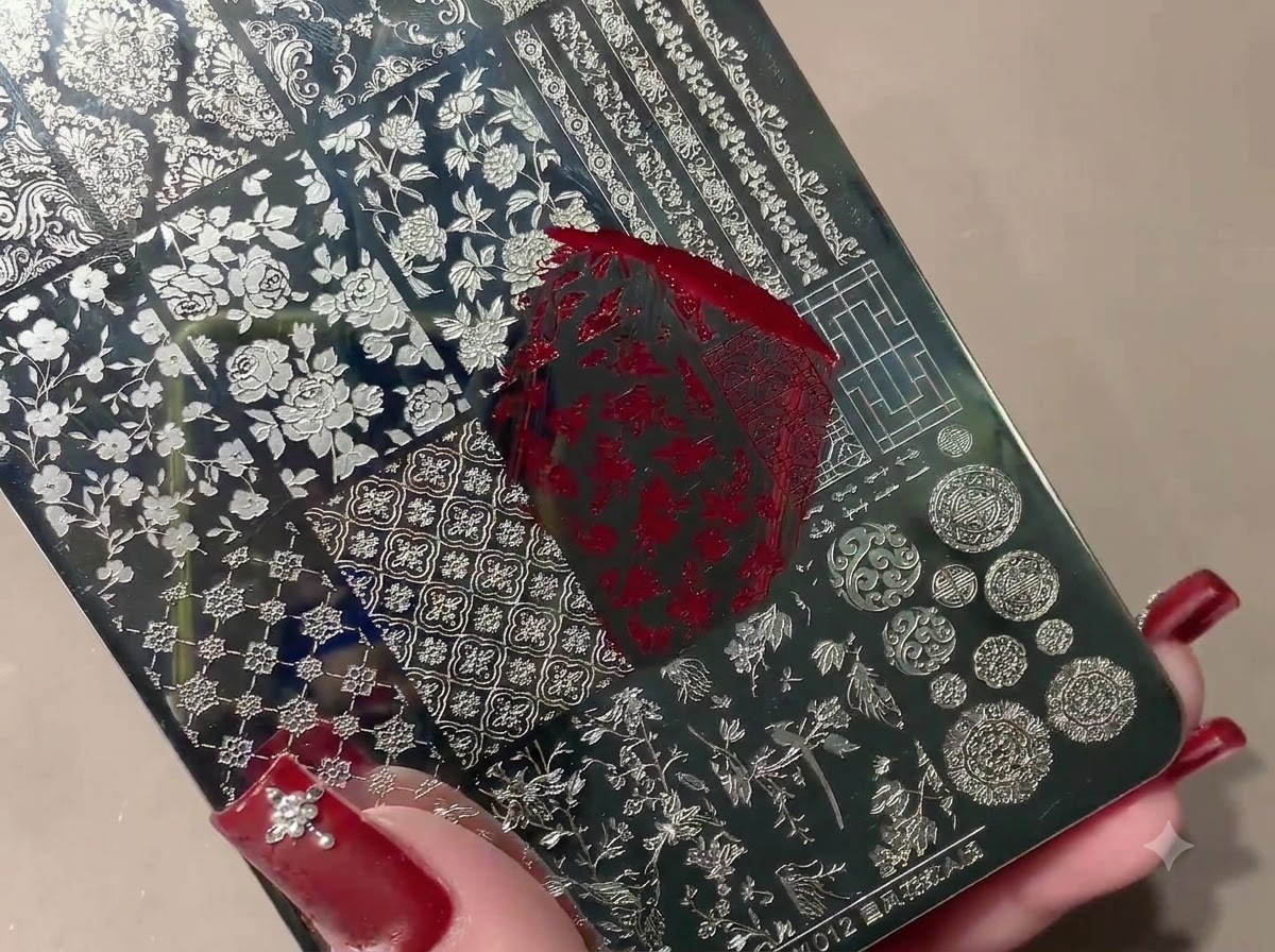 A silicone stamper picking up a red stamped pattern from a metal stamping plate.