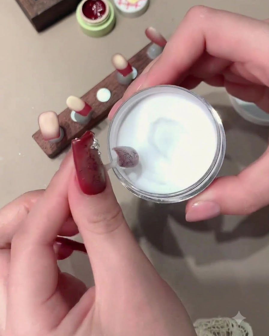 A red mini curing lamp being held over a nail to cure the product.