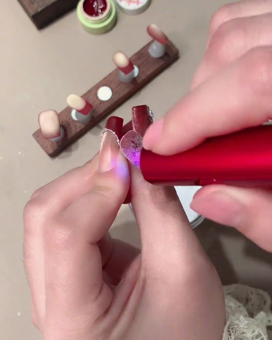 A soft brush removing excess white crystal powder from a decorated nail.