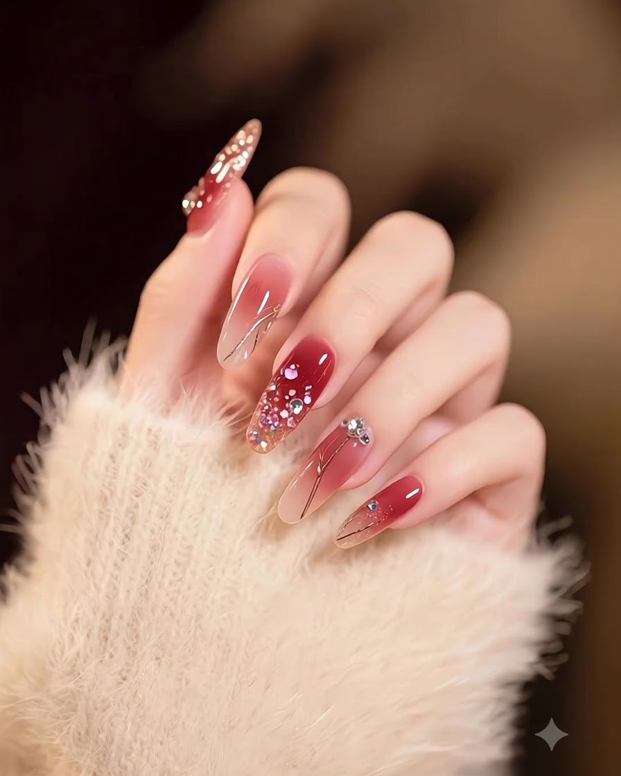 A hand showing long square nails with a smooth gradient from nude to deep burgundy, decorated with gold flakes.