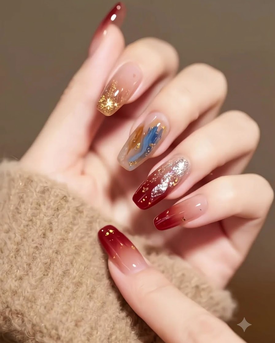 Detailed view of burgundy gradient nails with embedded stars and gold flakes against a textured beige background.