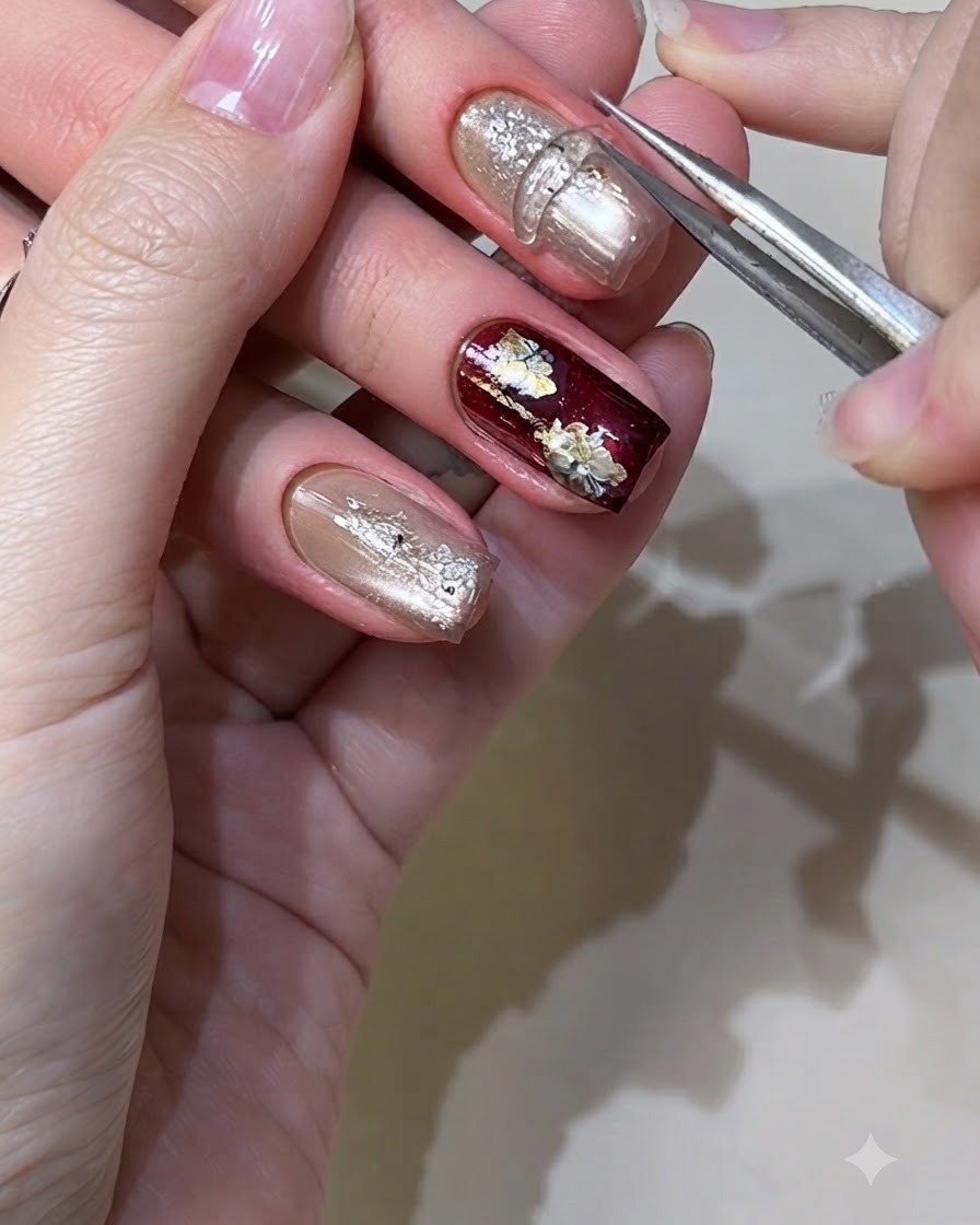 A pair of tweezers or a silicone tool pressing down a molded solid-state gel element onto a metallic gold nail.