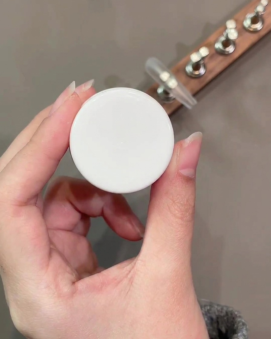 A flat gel brush applying a smooth layer of nude base color number 34 onto the nail surface.