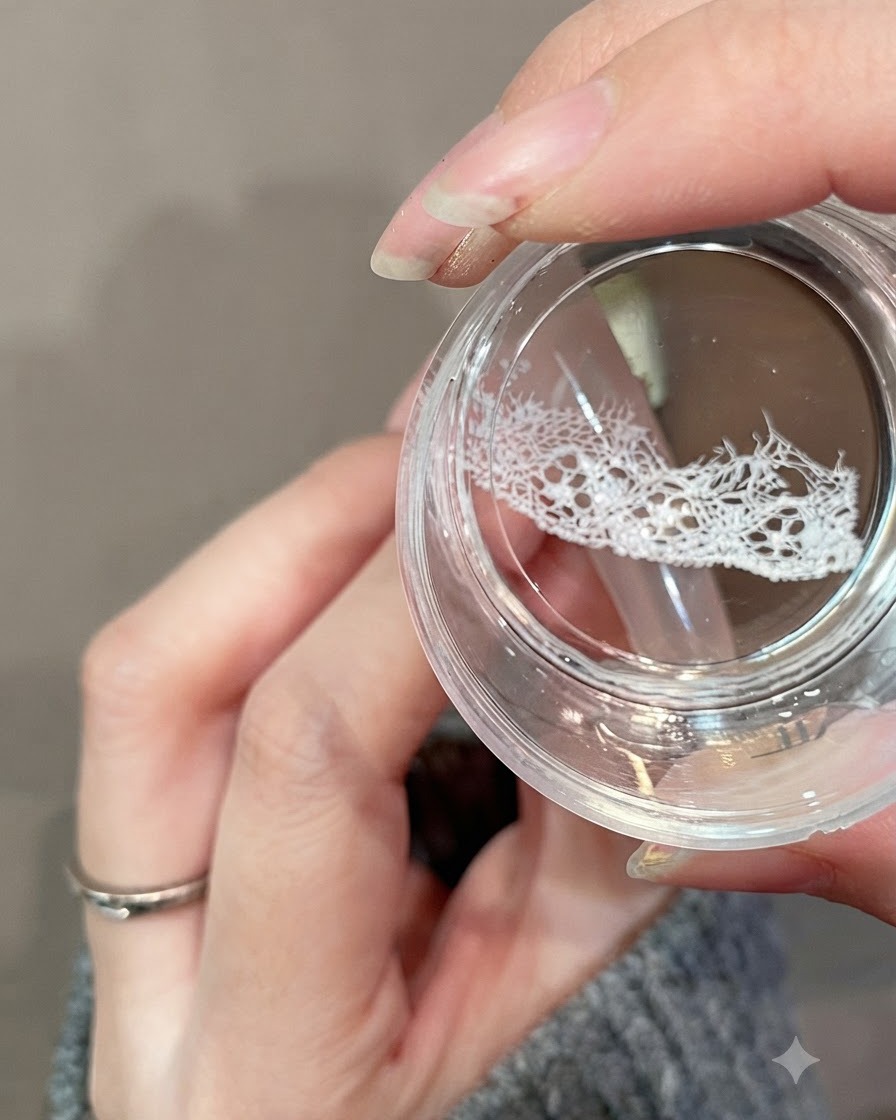 A clear jelly stamper transferring a delicate white lace design onto the upper portion of a nail.