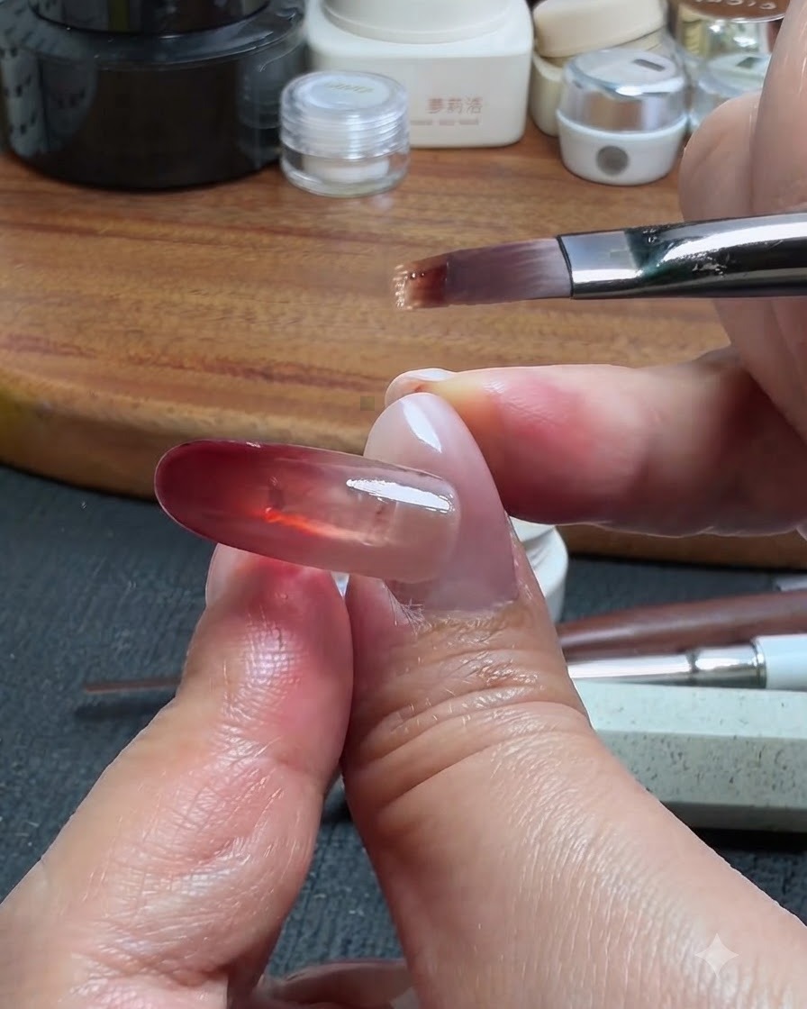 A nail brush picking up a tiny amount of base gel to drag upward from the red block, creating an ombre gradient effect.