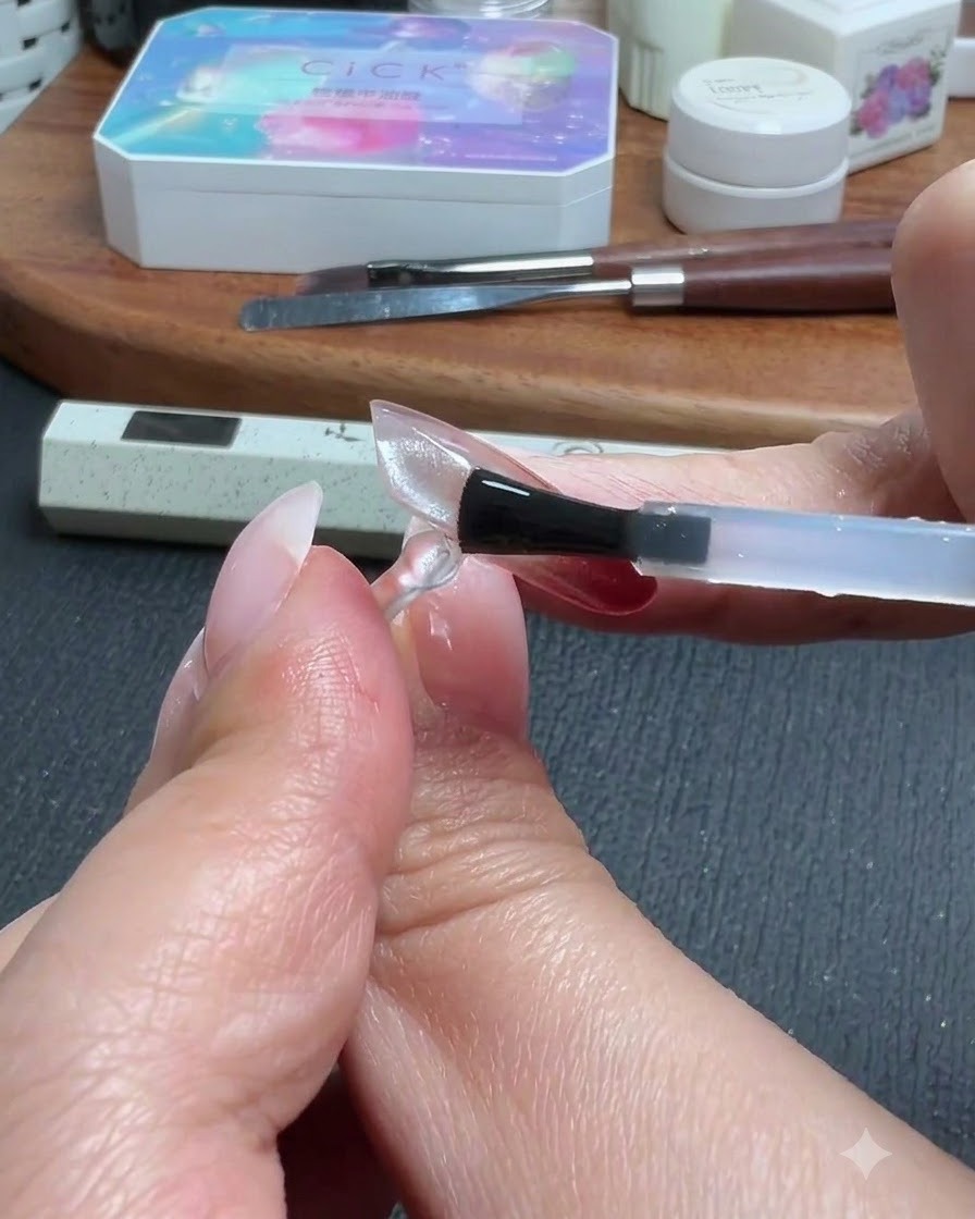 A brush applying a top coat layer over a clear translucent nail extension.