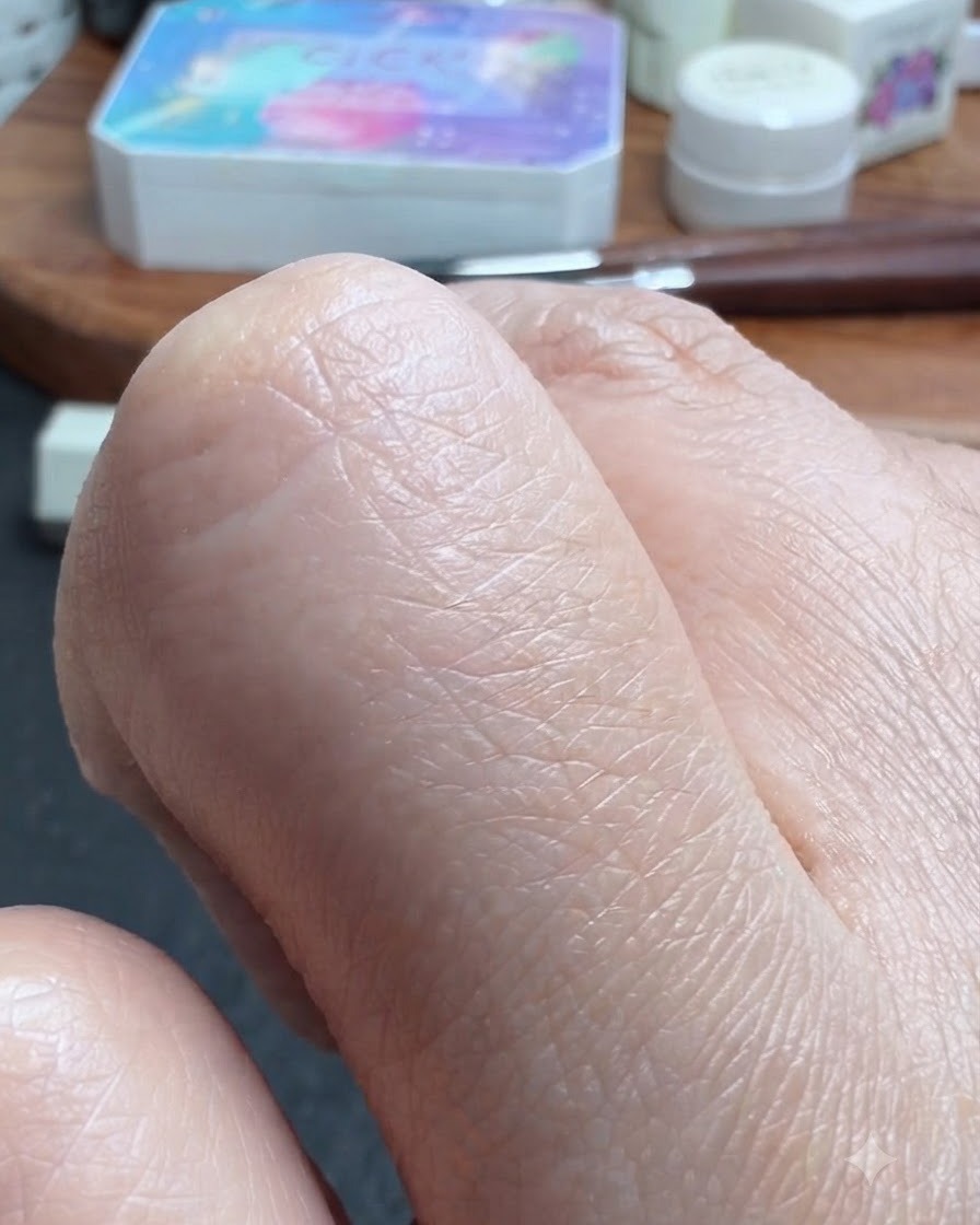 A close-up view of a thumb being lightly moistened with alcohol.