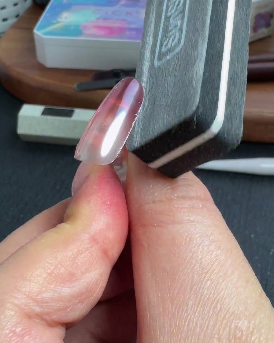 A nail file shaping the side edge of a finished chrome nail.
