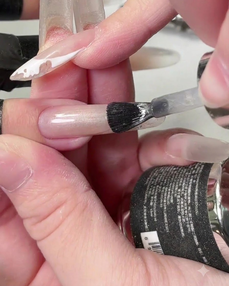 A brush applying clear crystal cat-eye gel across the length of the nail.