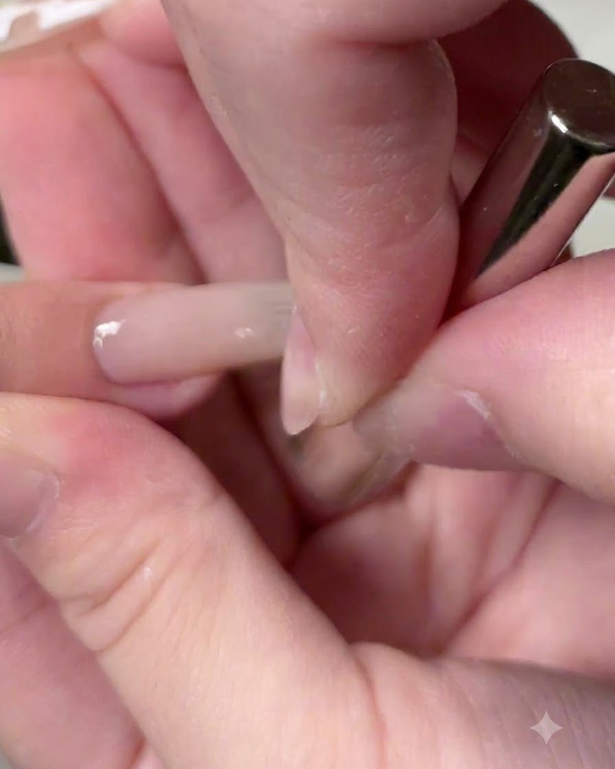 A magnetic tool hovering over the nail to draw the cat-eye pigment into a bright glass bead reflection.