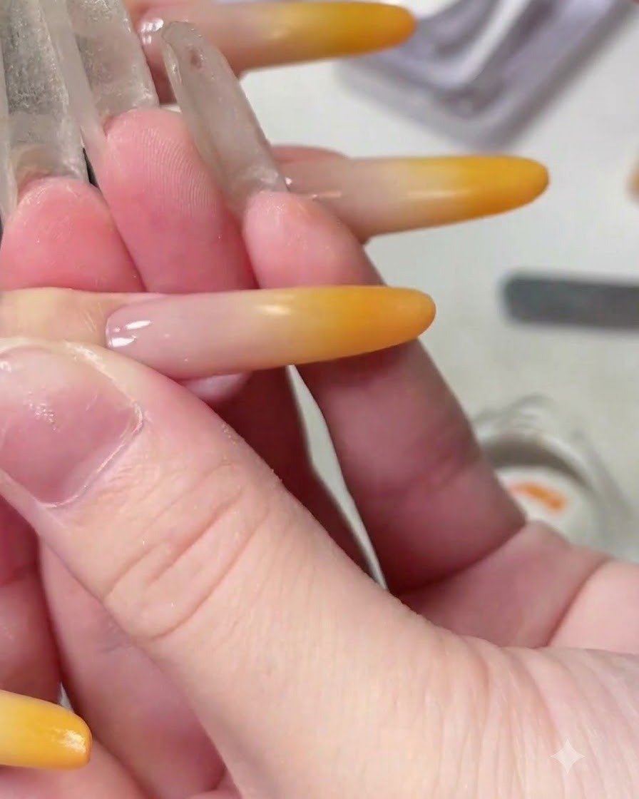 A close-up view of a fine liner brush drawing a delicate curved line on a completed gradient nail.