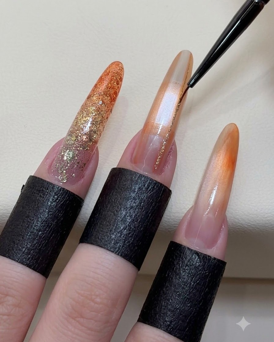 A fine liner brush applying sparkling champagne gold lines onto a decorated gel nail.