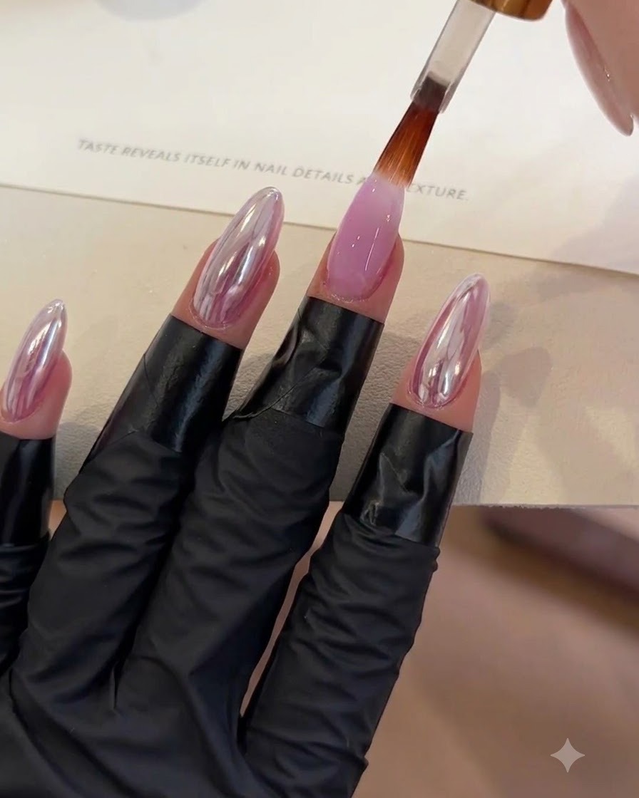A brush applying a clear top coat layer onto a purple gel nail.
