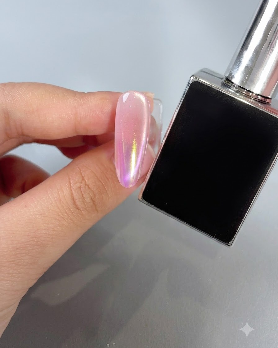 A manicured nail featuring a warm sunset-colored aurora powder gradient next to a polish bottle.