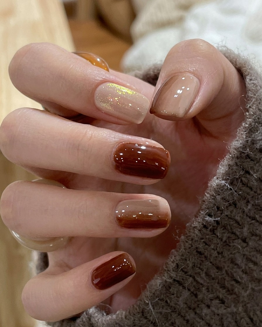 A close-up of a nail showing the blurred junction between brown and nude polish to form a smooth gradient.