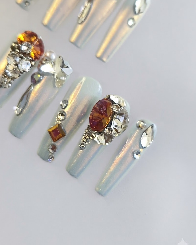 A close-up shot of long coffin-shaped false nails showcasing a smooth, iridescent pearlescent and chrome coating.