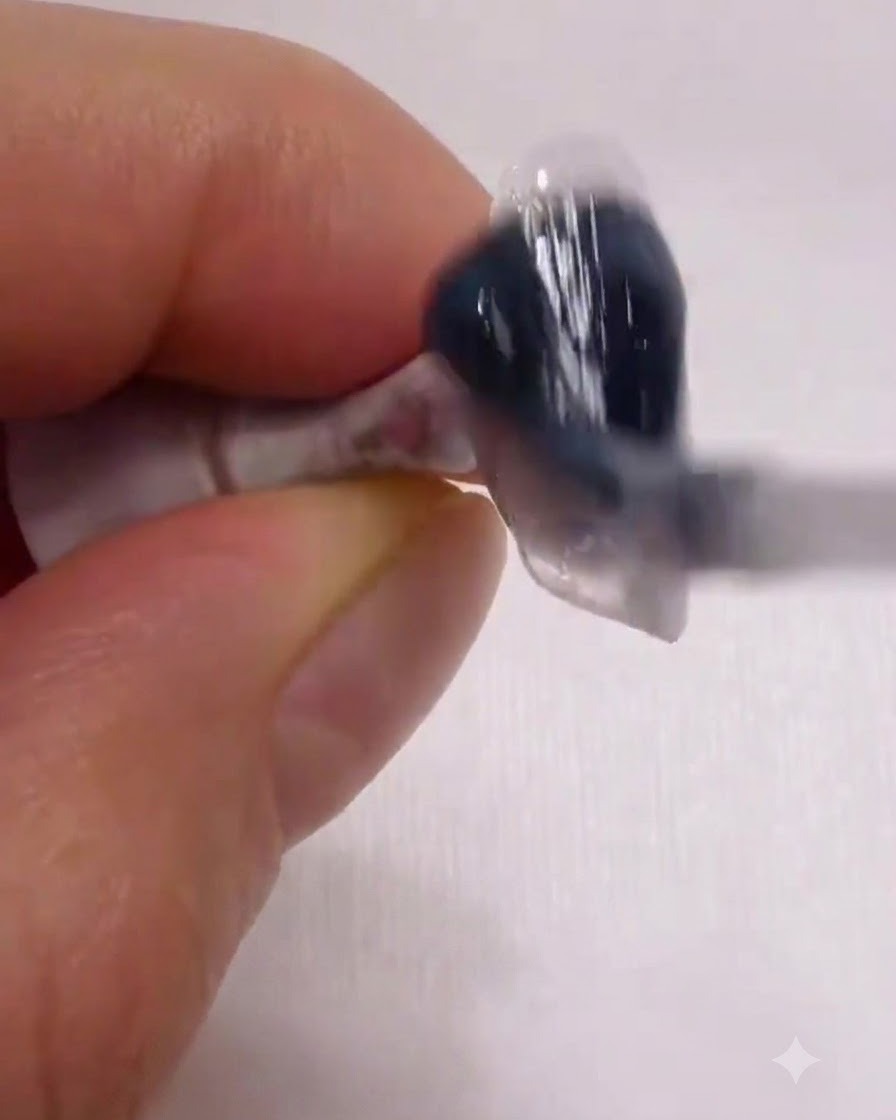 A brush gliding a smooth, milky white base coat evenly across the surface of a nail.