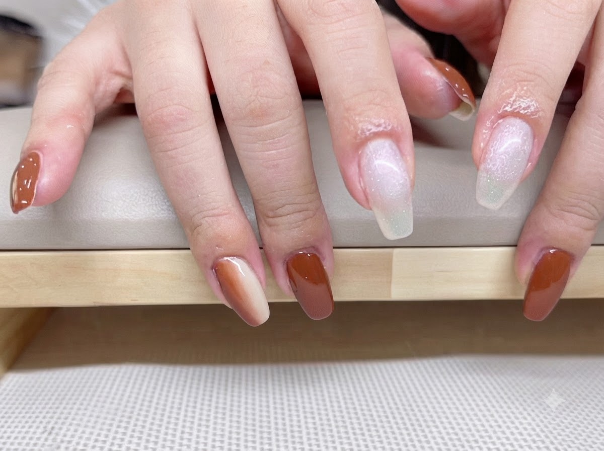 A close-up of hands with milky white translucent base coat applied to the index and middle fingers.