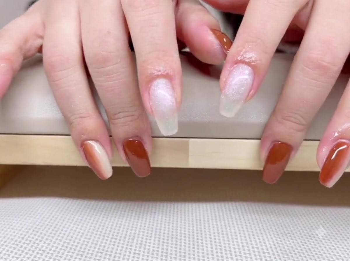 A view of hands showing rich caramel brown gel polish on the thumb, ring, and pinky fingers.