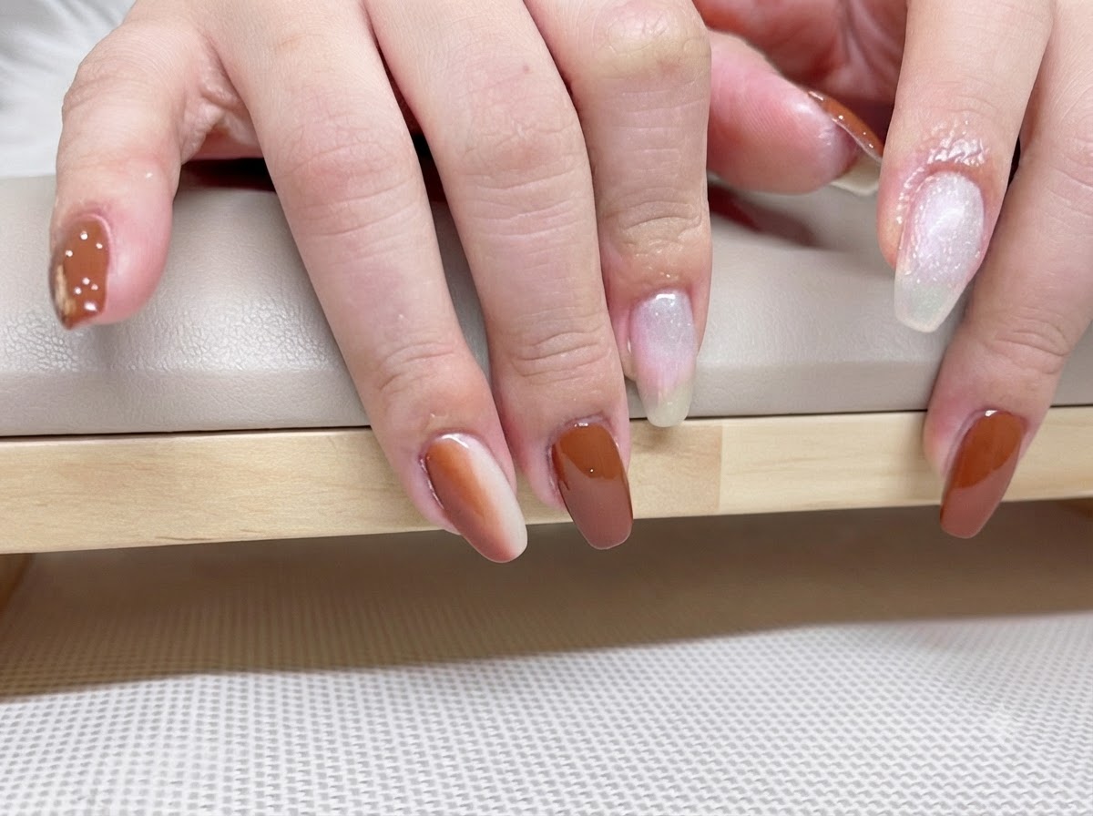 Detailed macro shot of finished caramel and amber gel nails reflecting light under a gloss top coat.