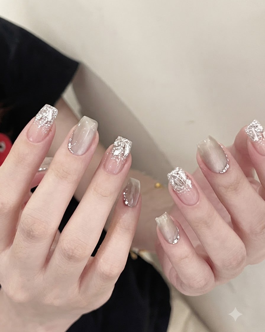 A pair of metal tweezers holding a sparkling clear crystal rhinestone and placing it onto the base of a manicured nail.