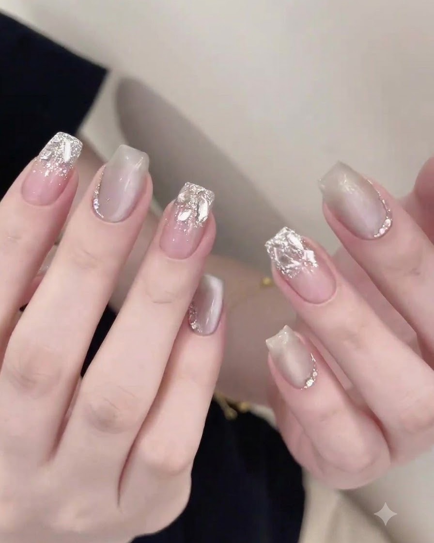 A nail brush carefully applying a glossy top coat around embedded rhinestones on a finished nail.