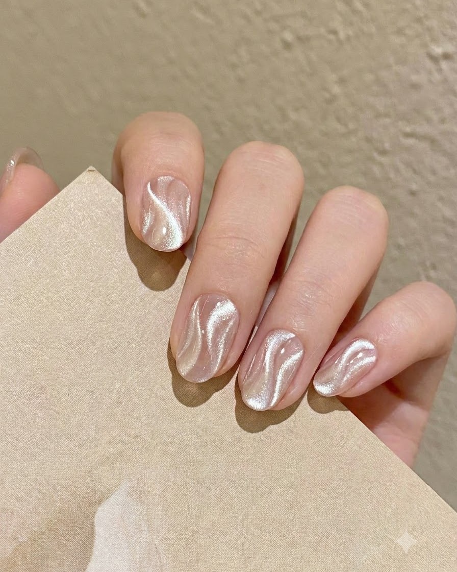 A fine nail art liner brush picking up a small amount of shimmering silver cat eye gel from the palette.