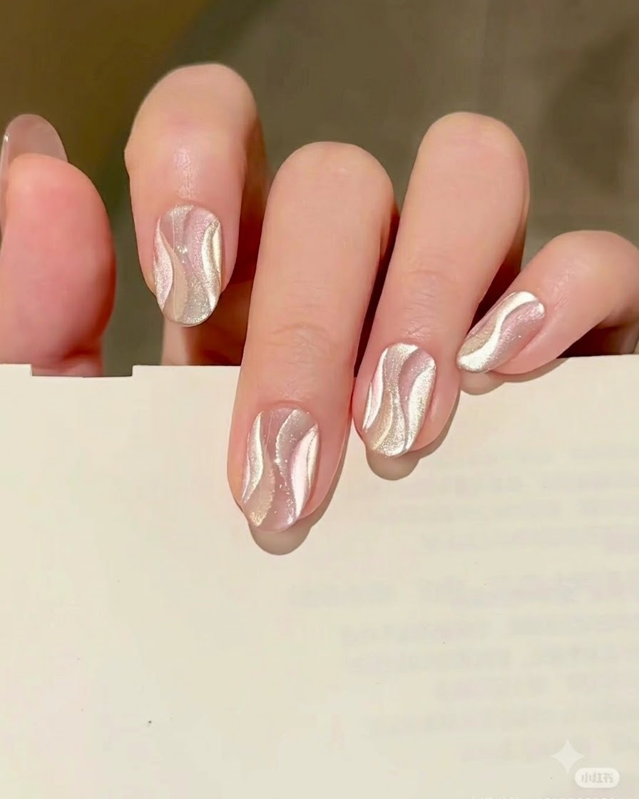 A fine liner brush painting a second curving ribbon shape using gold cat eye gel right next to the cured silver ribbon.