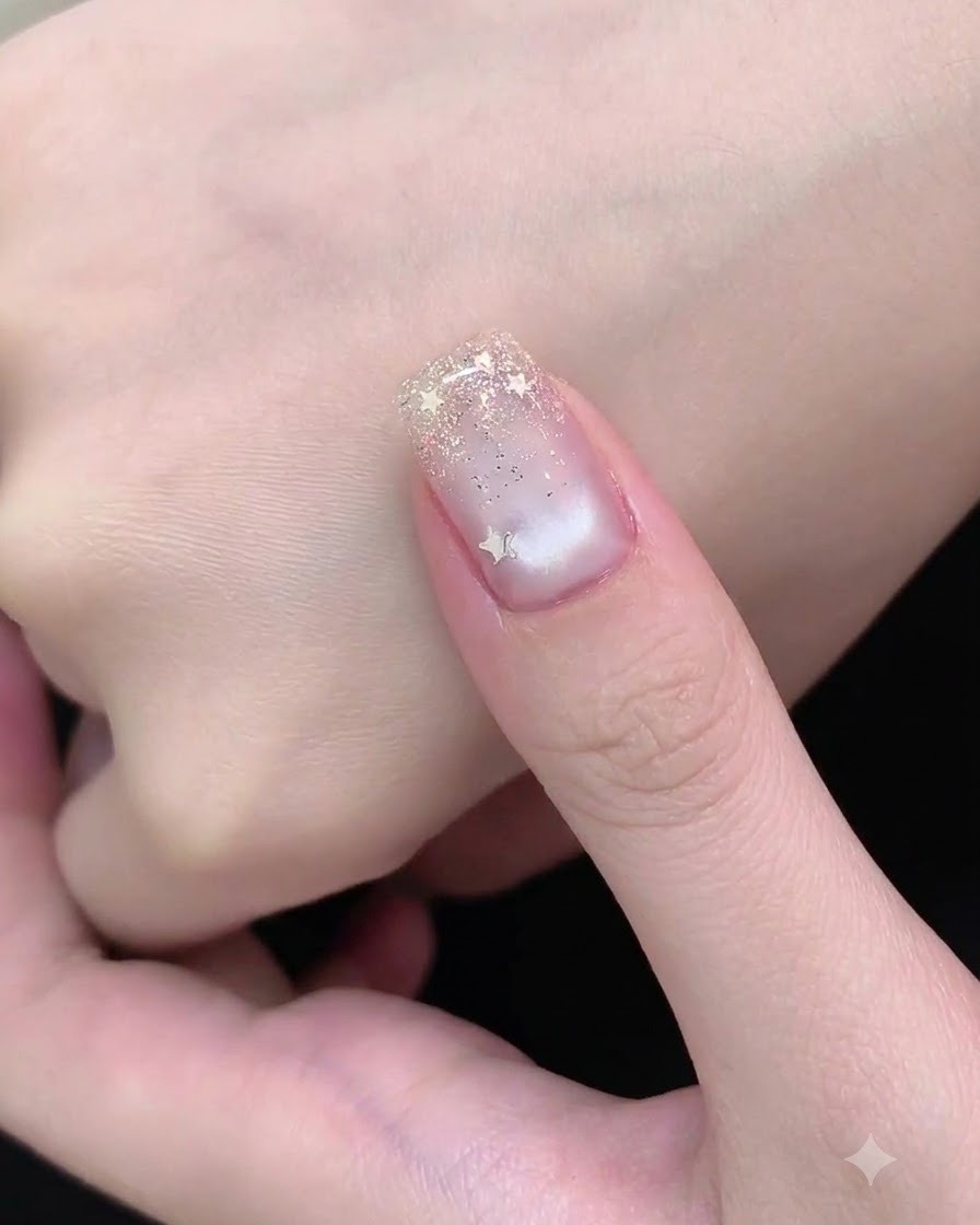 A nail art brush dabbing fine silver glitter onto the free edge of the nail to form a gradient.