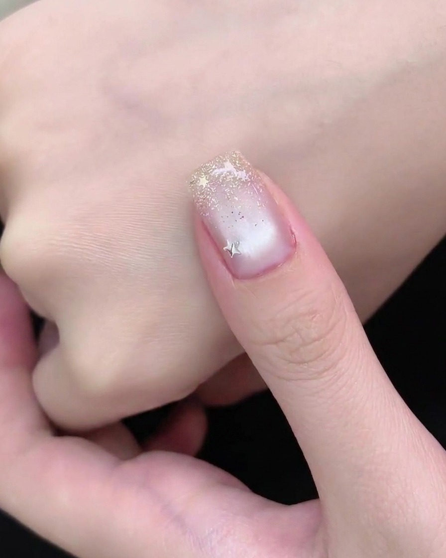 A hand resting under a UV or LED nail lamp during the final curing stage of a manicure.