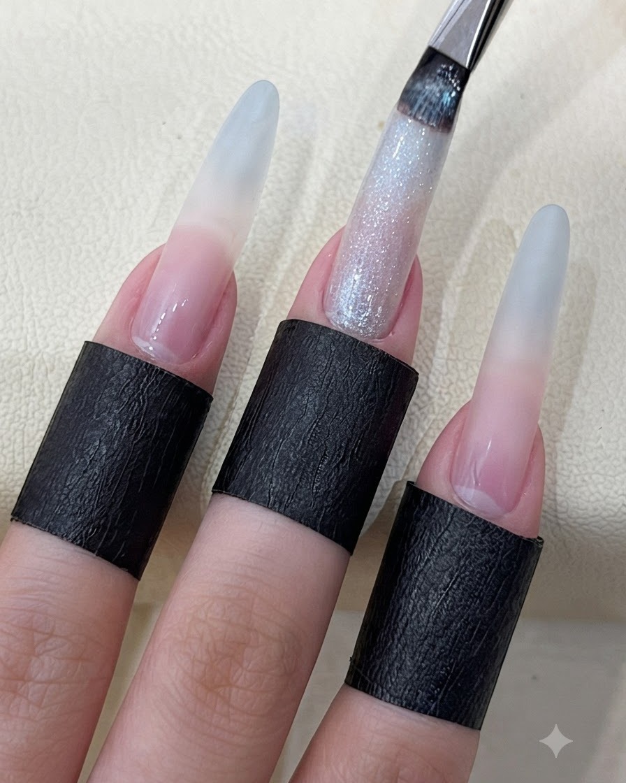 A nail brush applying shimmering starry cat eye gel onto a long sculpted fingernail.