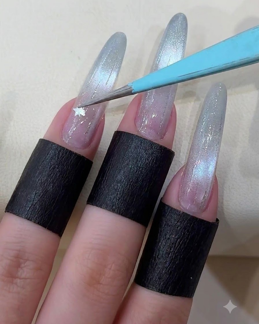 A pair of tweezers placing a small metallic star sticker onto a decorated long nail.