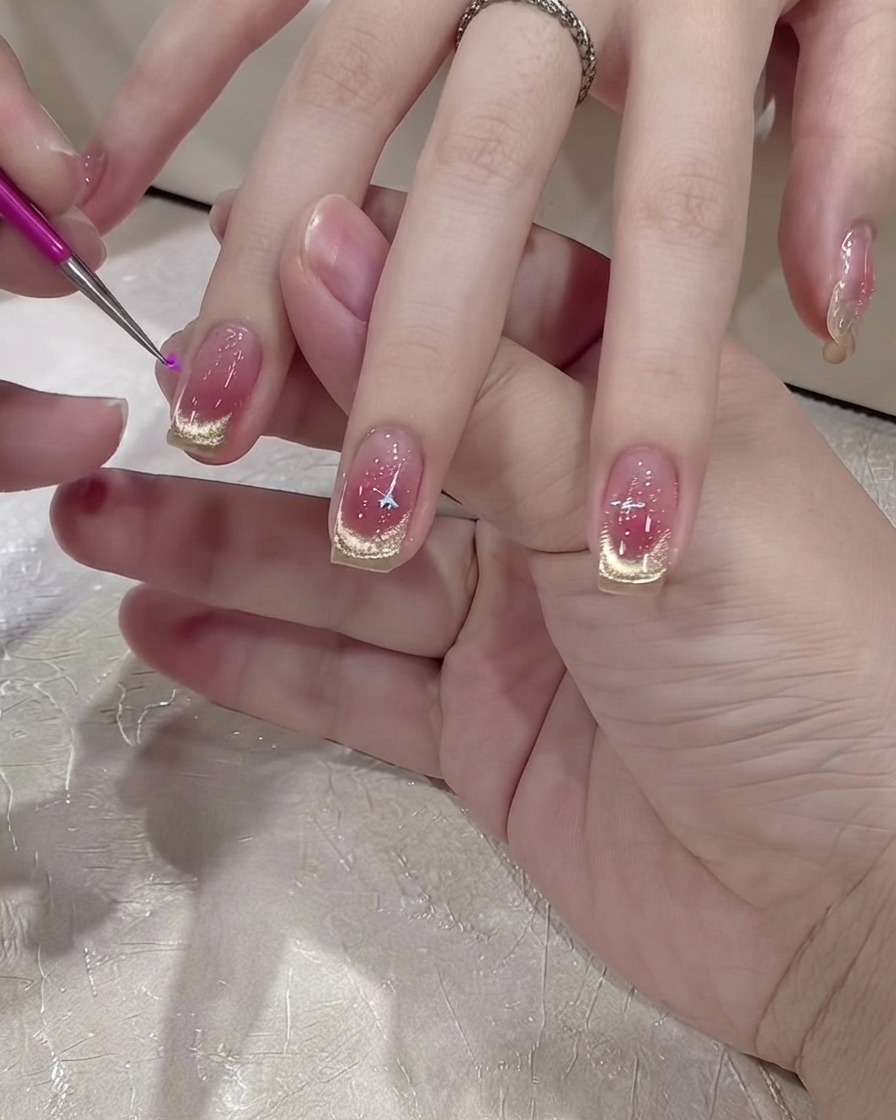 A fine tool or stylus placing a silver star sticker onto the nail surface.