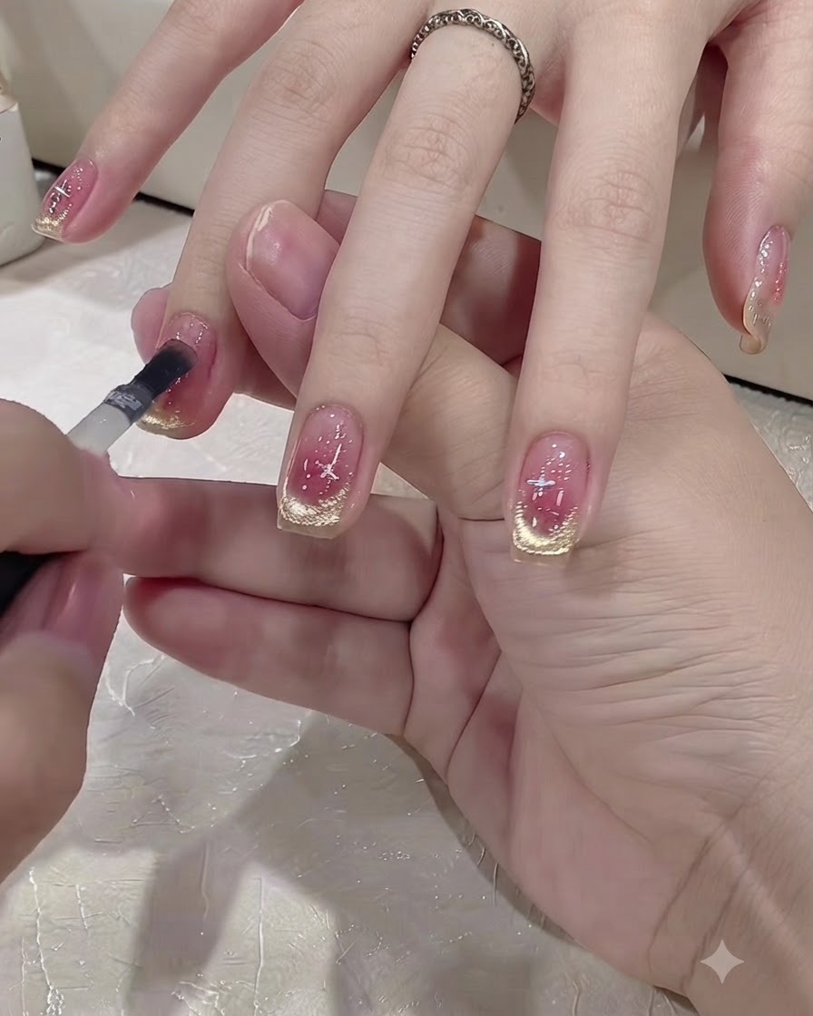 A small brush applying a clear top coat layer onto a decorated nail.