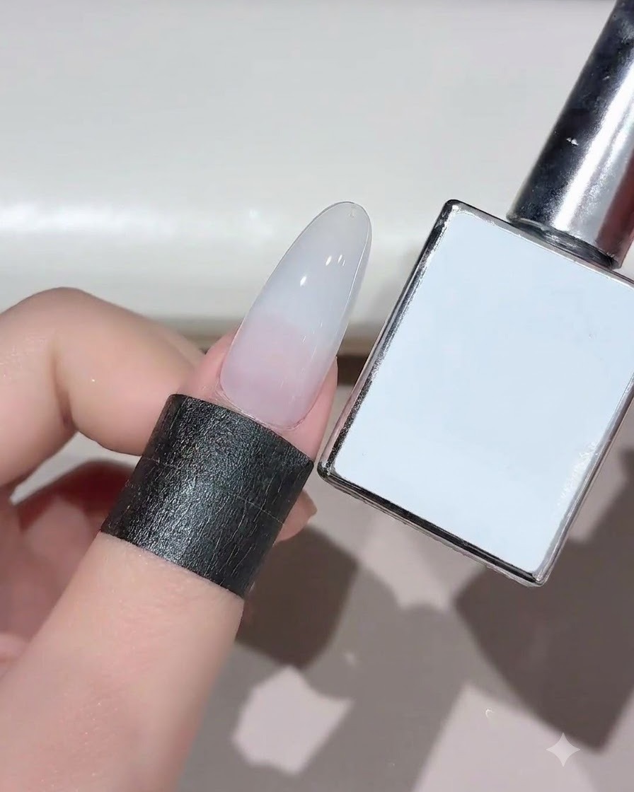 A nail with cured milky white gel shown next to its product bottle.