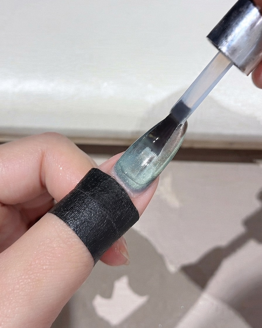 A nail brush applying a clear top coat over a mirror-finished green powder gradient nail.