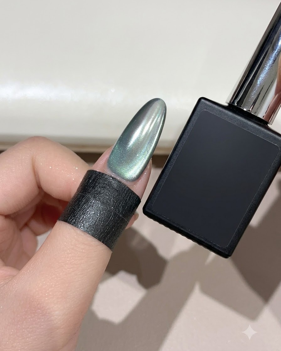 A finished almond-shaped cyan mist crescent moon cat-eye nail next to a black gel bottle.