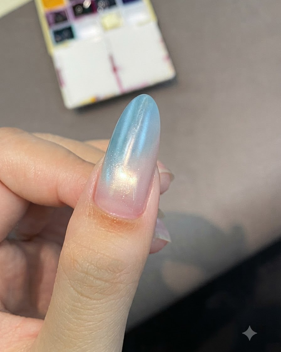 An almond-shaped nail with a soft blue-to-pink gradient, showing a curing shine under lighting.